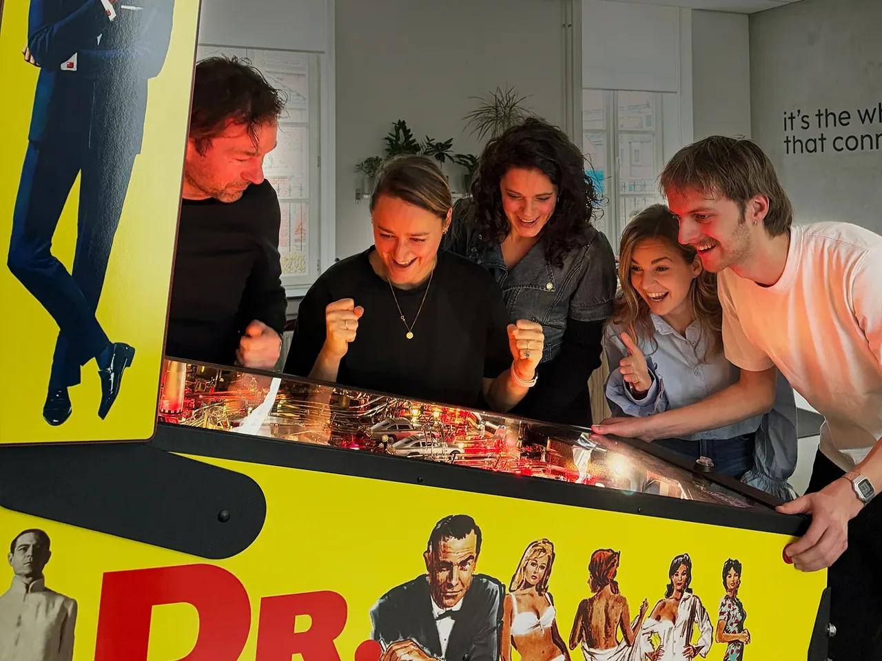 Vijf mensen spelen samen op de James Bond flipperkast, gehuurd bij Flipperkasthuren.nl