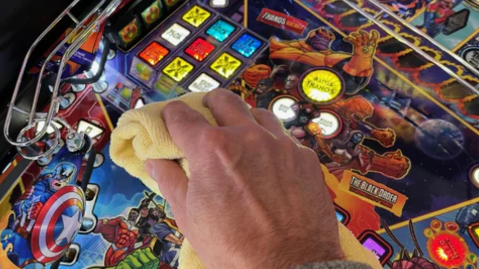 Het speelveld van een flipperkast wordt schoongemaakt