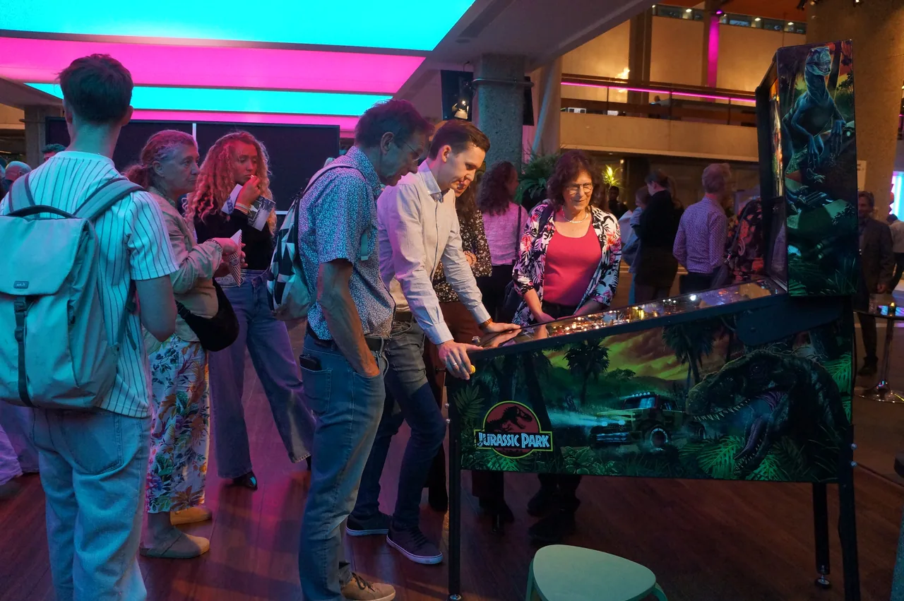 Concertbezoekers aan de Jurassic Park flipperkast in de foyer van de Doelen